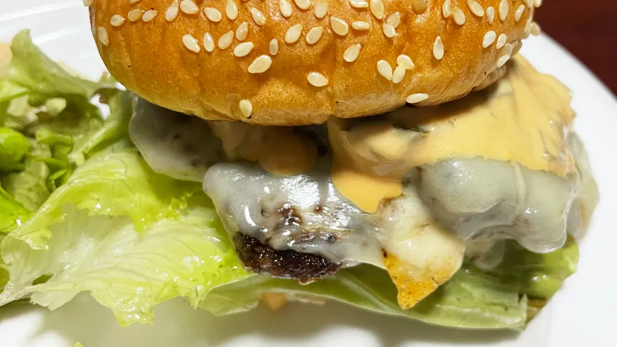 完成したハンバーガーの寄りの画像(はみ出るレタス、とろけるチーズがポイント)