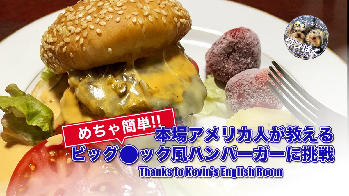 セサミバンズにチーズがとろける自家製ビッグ◯ック風ハンバーガー。レタスとトマトを添えた皿のクローズアップ、フォーク付き