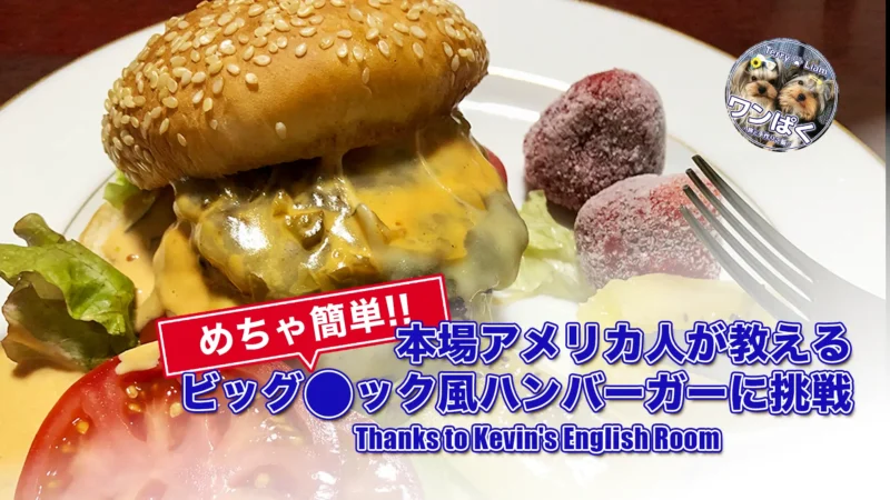 セサミバンズにチーズがとろける自家製ビッグ◯ック風ハンバーガー。レタスとトマトを添えた皿のクローズアップ、フォーク付き