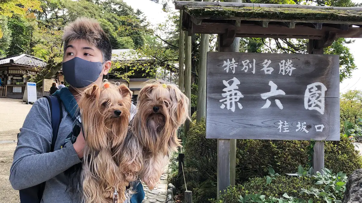 「兼六園(桂坂口)」の看板の前で記念撮影するヨーキーズ(テリー&リアン)