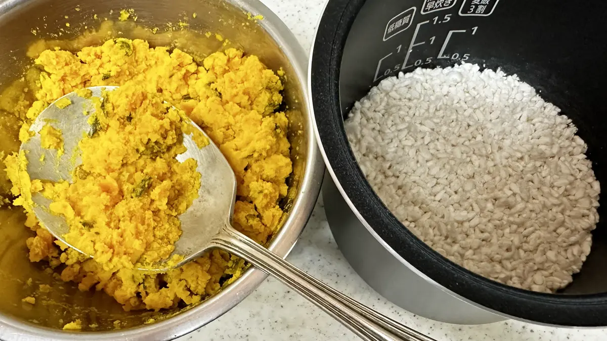 ボウルに入ってスプーンで潰した蒸したカボチャ200gと、炊飯器に乾燥麹100g