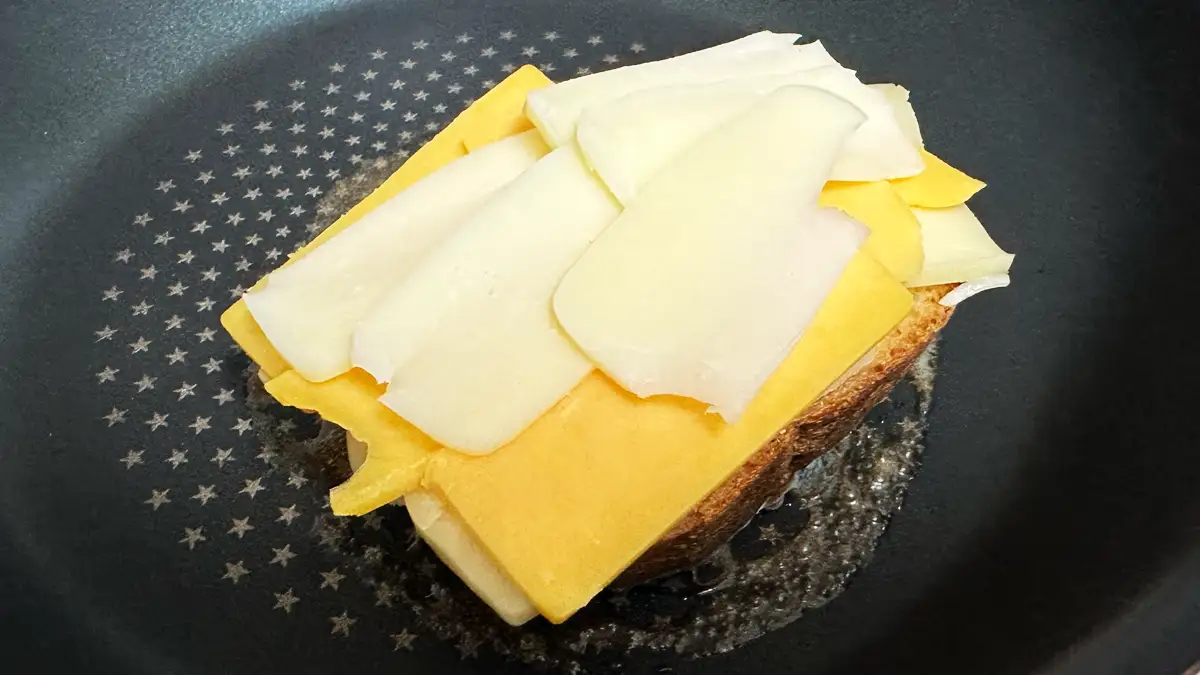 焼いたパンにはみ出るほど盛られた3種のチーズ（レッドチェダー、モッツァレラ、ゴーダチーズ）