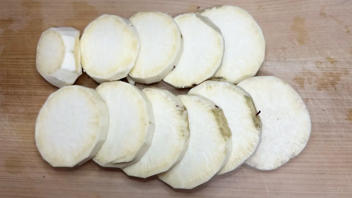 水洗いしたさつまいもの皮を剥き、1cm幅に切ったものが木のまな板の上に並んでいる