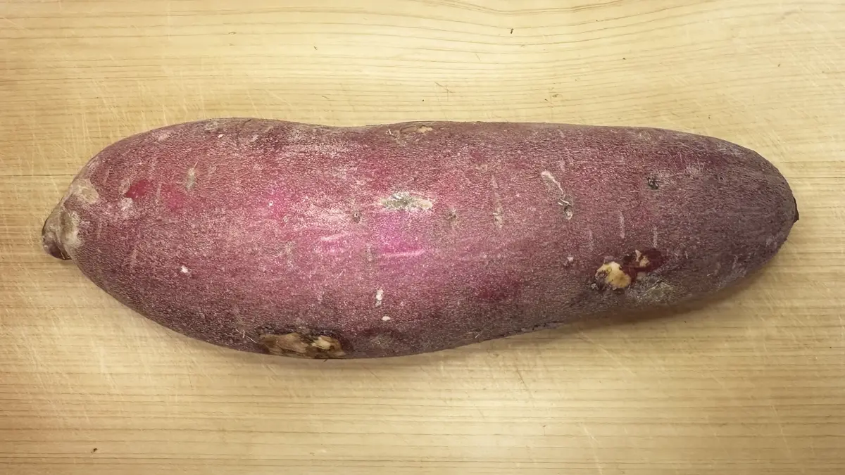 木のまな板の上に置かれたさつまいも