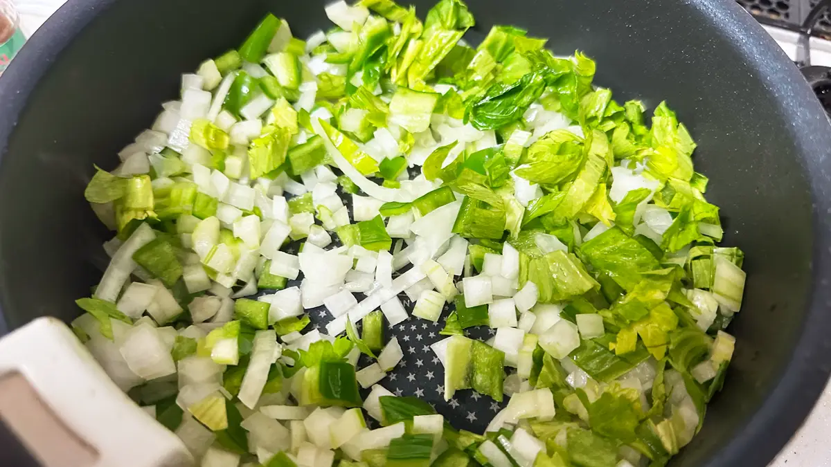 鍋を使って炒められている野菜(Holy Trinity)