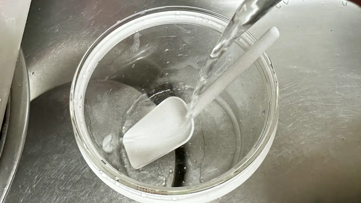 ヨーグルティアSの内釜（ガラス製）と付属のスプーンに熱湯をかけ消毒している様子。火傷に注意！