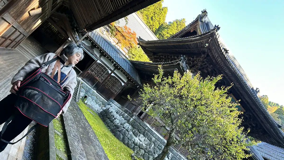 「大本山 永平寺」さんの中庭で記念撮影する人間（けい）とヨーキーズ（テリー&リアン）。けいはカッコつけてカメラから目線を外し、ヨーキーズはおとなしくカバンにIN！