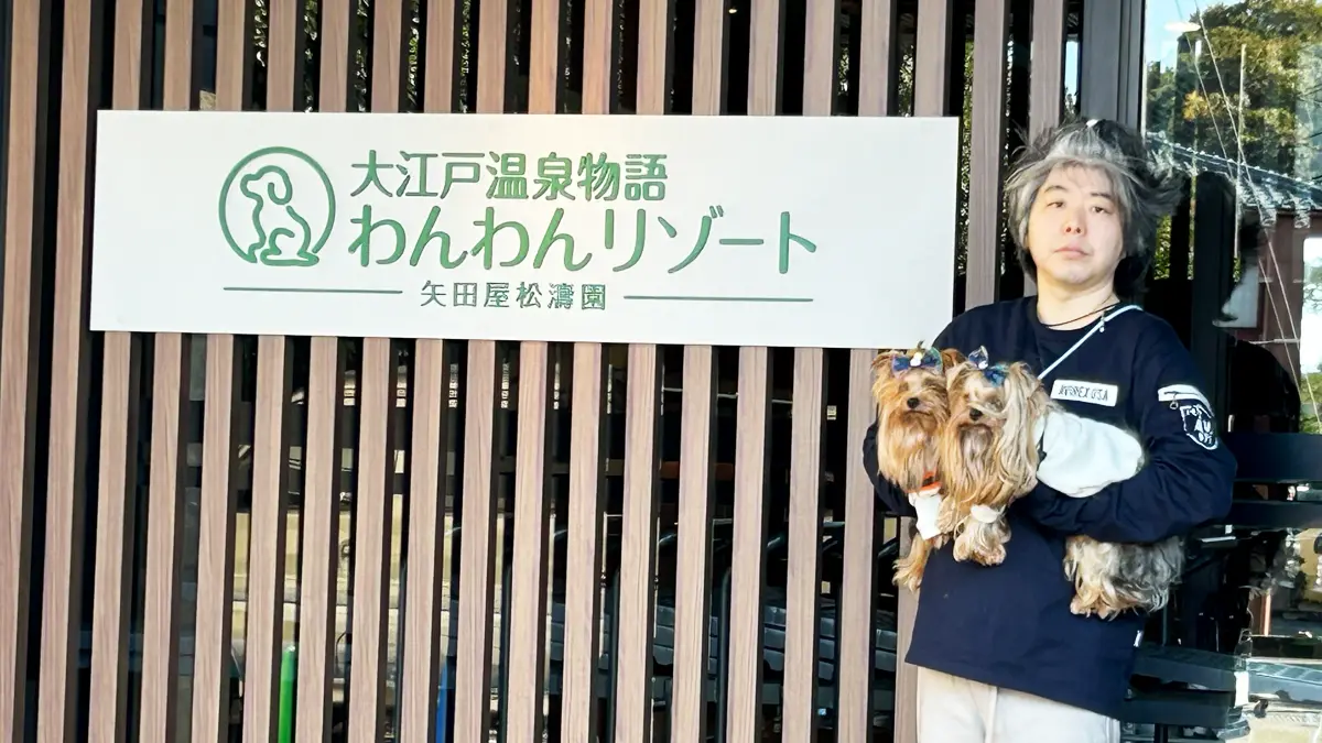 「わんわんリゾート矢田屋松濤園」さん入り口にある看板の前で記念撮影する人間（けい）に抱っこされるヨーキーズ（テリー&リアン）