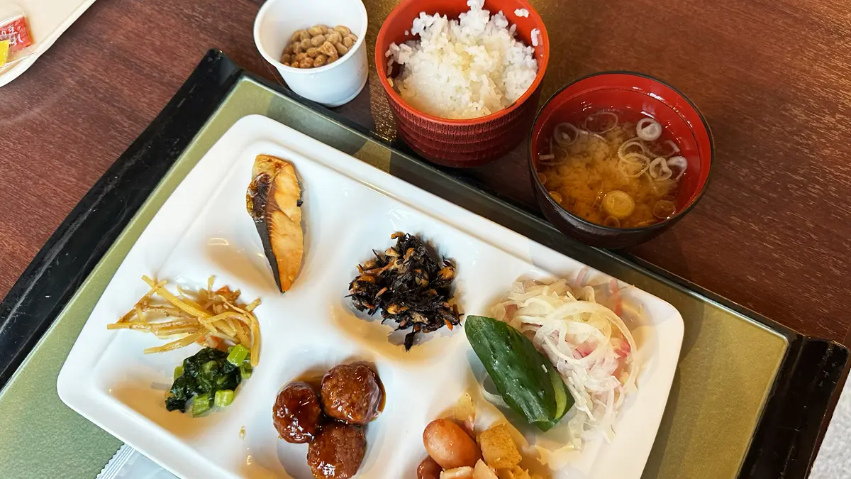 「高山わんわんパラダイス」の朝食バイキング。6つに区分けされたプレートに鮭やひじき、ミートボールが並ぶ。そのほかに白米と納豆と味噌汁と純和風の朝食。