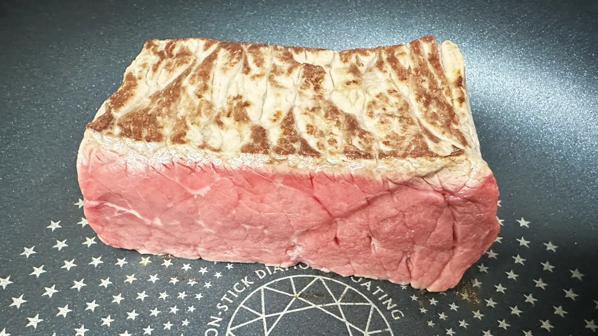 フライパンの上にお肉を乗せ表面を焼いている。うっすら焦げ目がついているが、中身は赤いまま