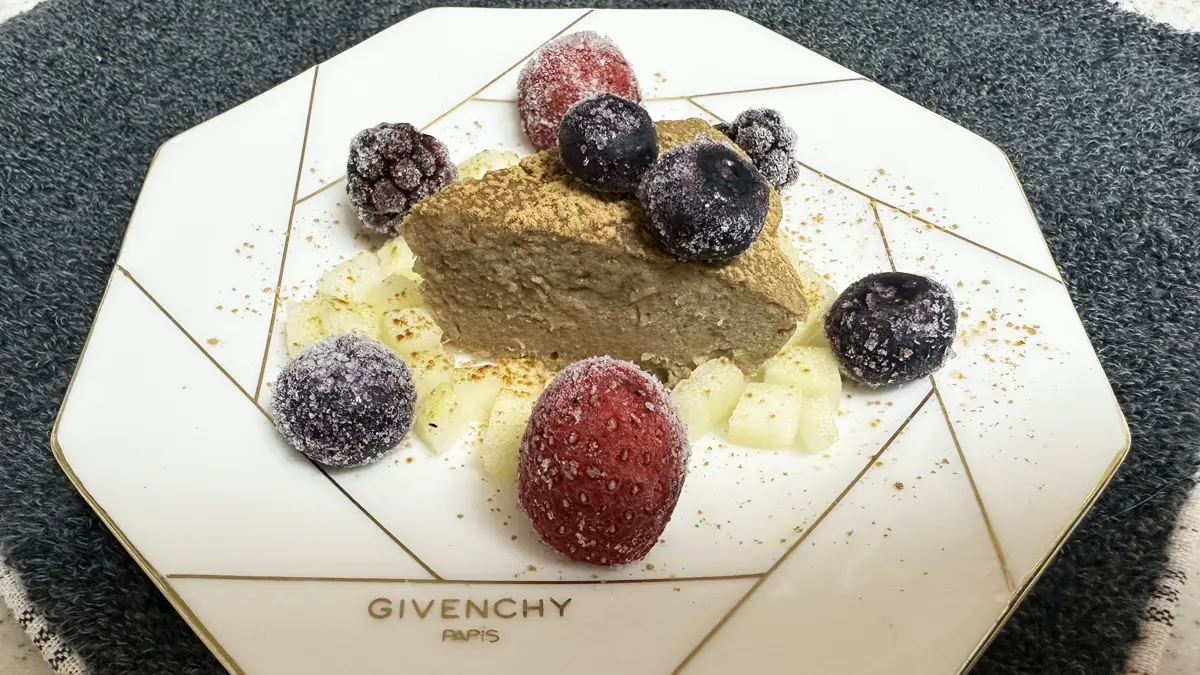 ジバンシーのお皿にキャロブケーキ、りんご、ミックスベリー、キャロブぱうだーをふりかけデコレート