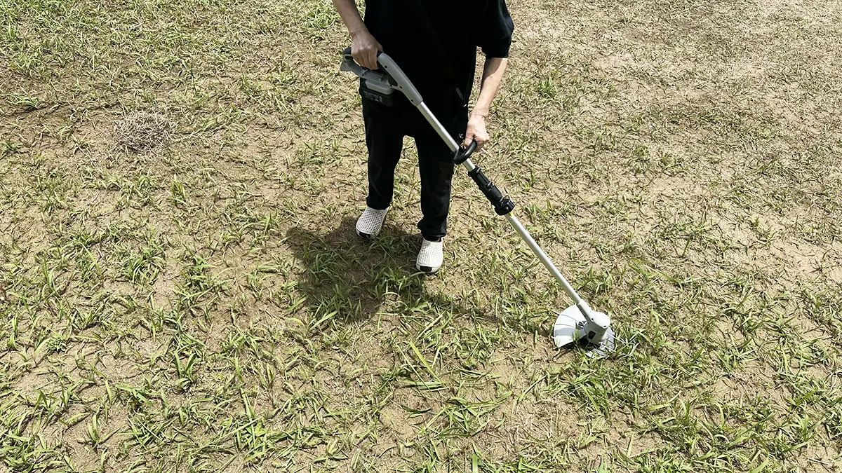 自宅の庭の草刈りをしているばあば。18Vの充電式草刈機を使っている